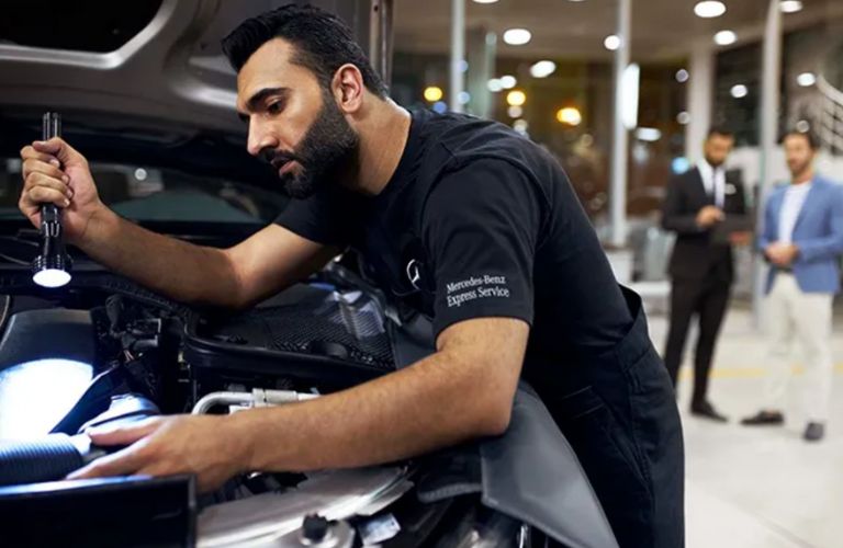a Mercedes-Benz technician working under the hood of a car