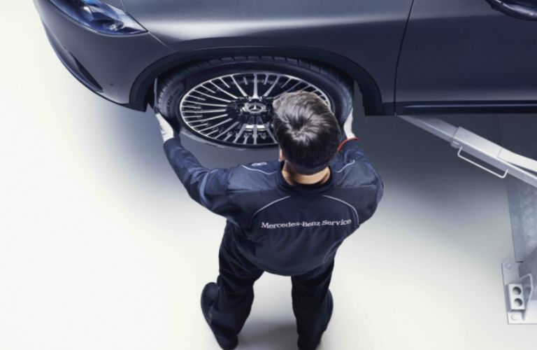 a technician inspecting the tire of a Mercedes-Benz