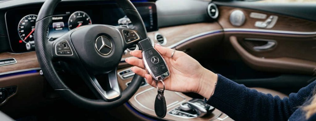 A woman holding a Mercedes-Benz key fob