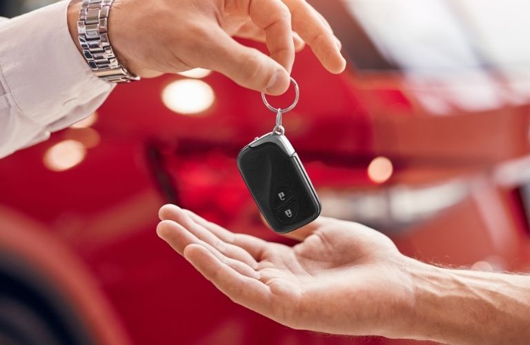 A person handing over a car key to another
