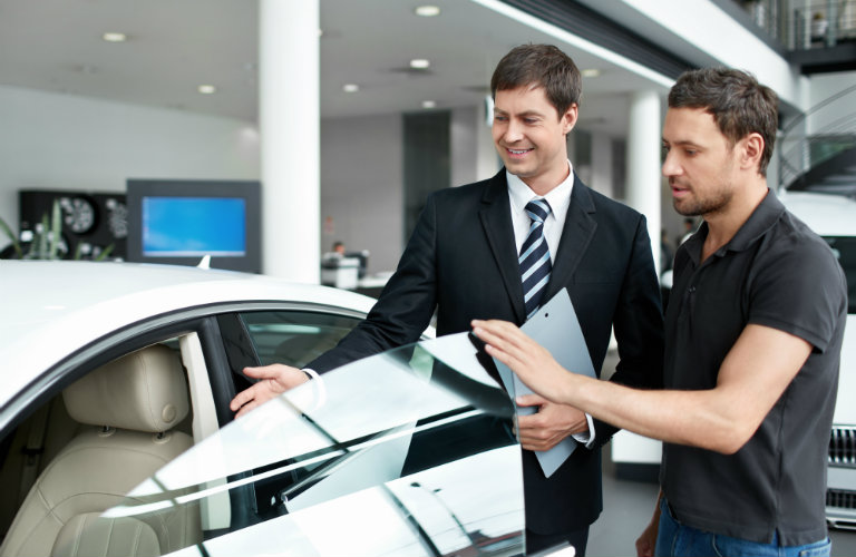 Two people taling to each other and opening the front door of a car