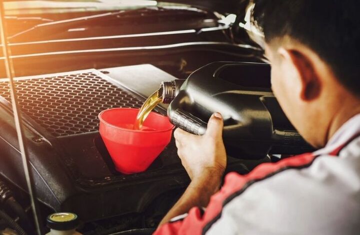 Mechanic pouring oil in a car engine