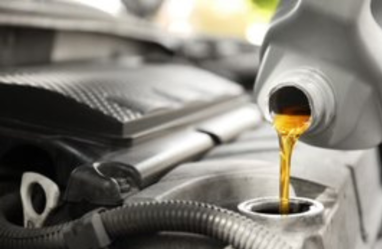 A mechanic adding oil to a vehicle 