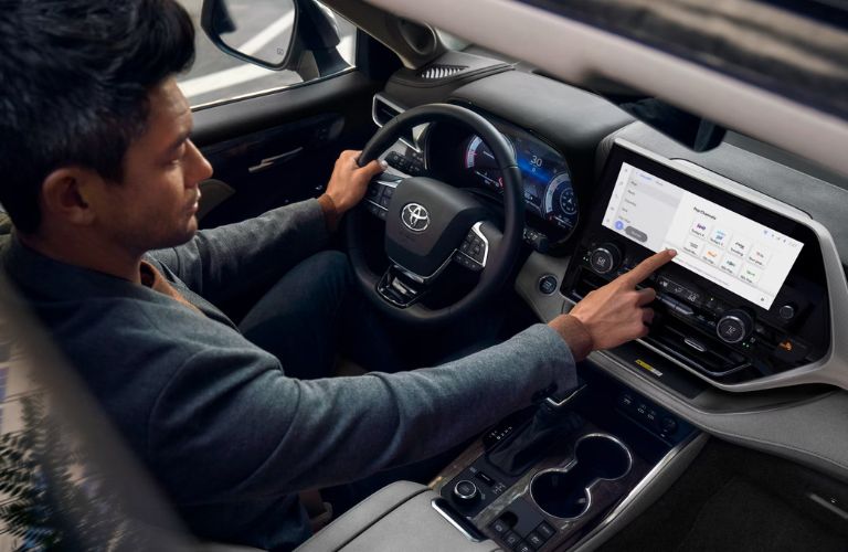 Driver operating the center touchscreen in the 2025 Toyota Highlander