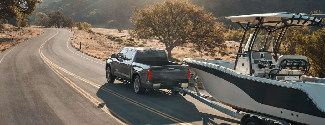 The 2026 Toyota Tundra towing a large boat on a rural road