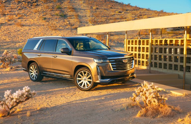 2021 Cadillac Escalade exterior shot with brown metallic paint color parked near a building in a dry desert area