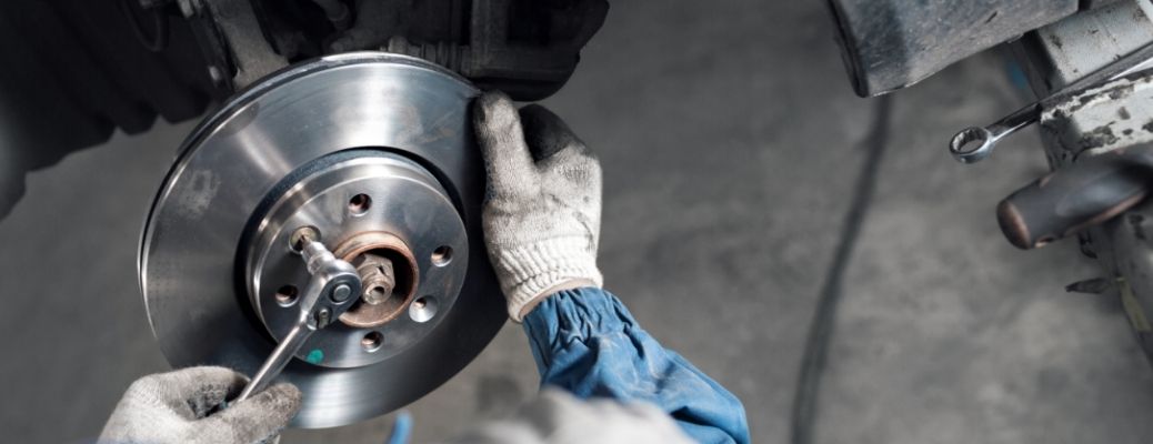 a technician wearing gloves inspecting the brakes of a car
