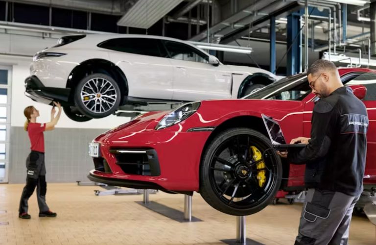 technicians inspecting Porsche models at a service center