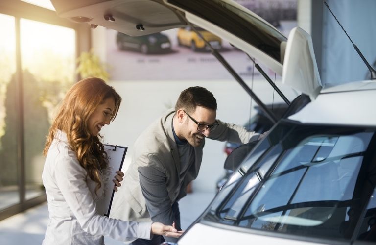 a woman and a man inspecting a car