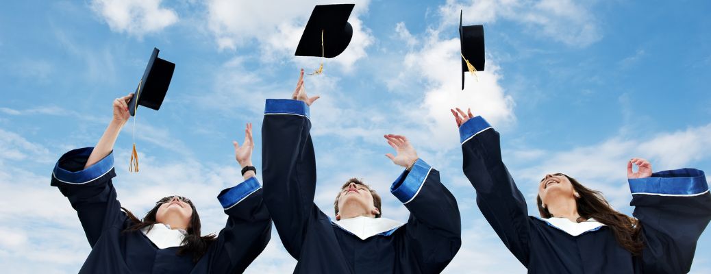 three graduates flipping hats in the air
