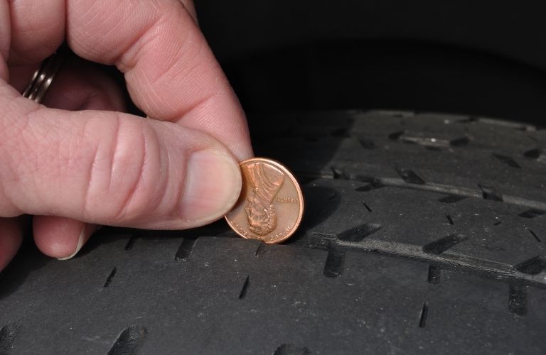 closeup of a hand doing the penny test on a tire