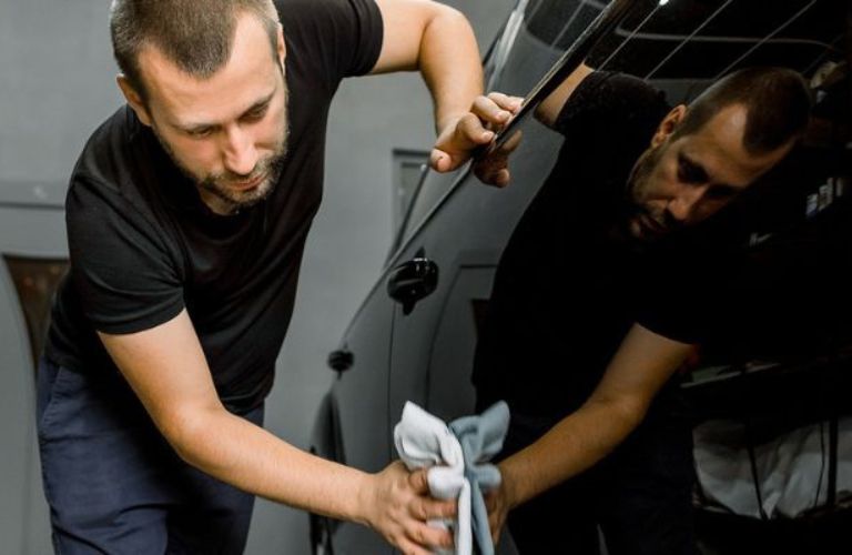 a technician cleaning the exterior of a car