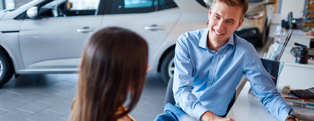 a man and woman talking at a dealership