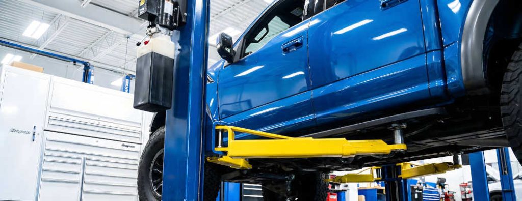 A truck being serviced in an automotive repair shop, including a pickup truck coolant system check.