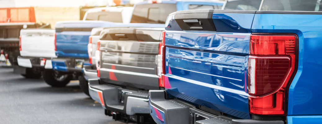 A rear exterior view of a series of pickup trucks for sale at a used truck dealership