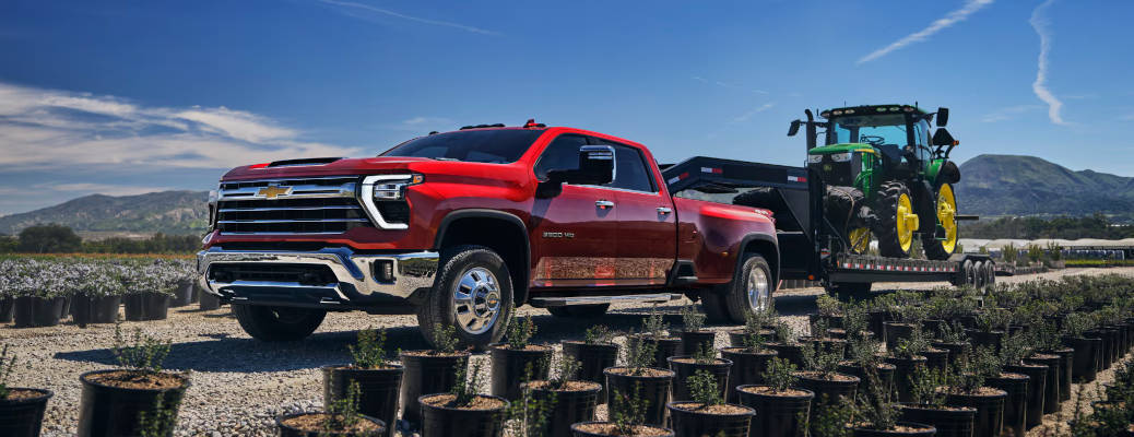 A Silverado 2500 HD towing a large trailer with a tractor on it