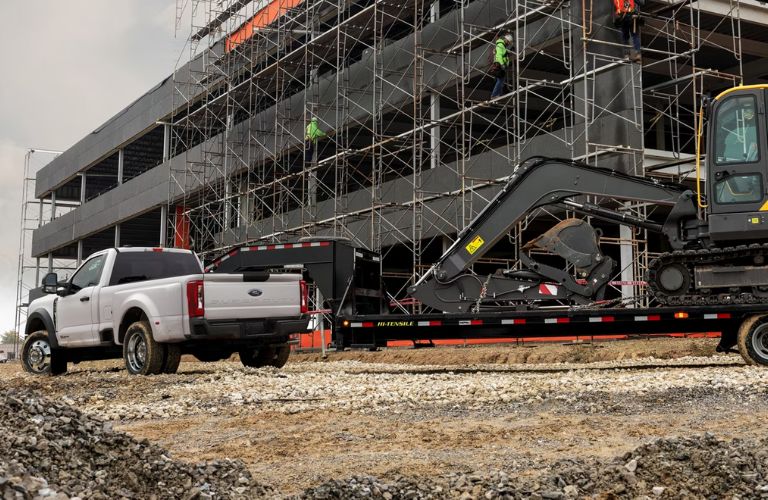 A Ford F-250 towing machinery at a construction site