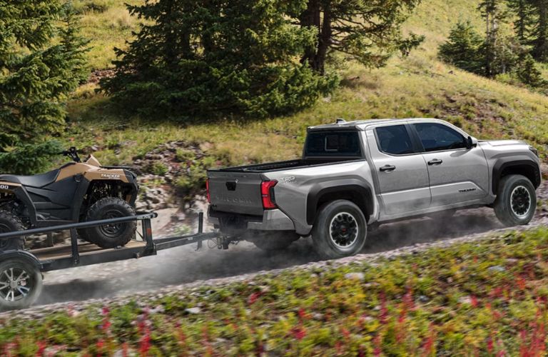 Toyota Tacoma towing an ATV on uneven terrain