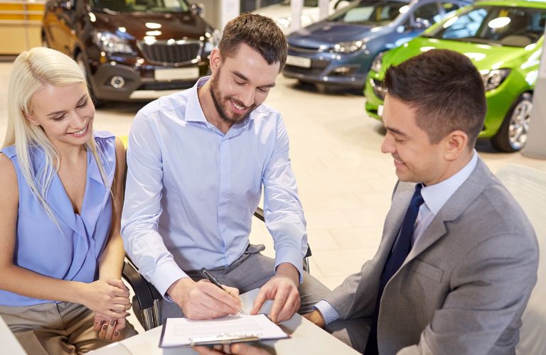 Couple signing papers with a sales representative