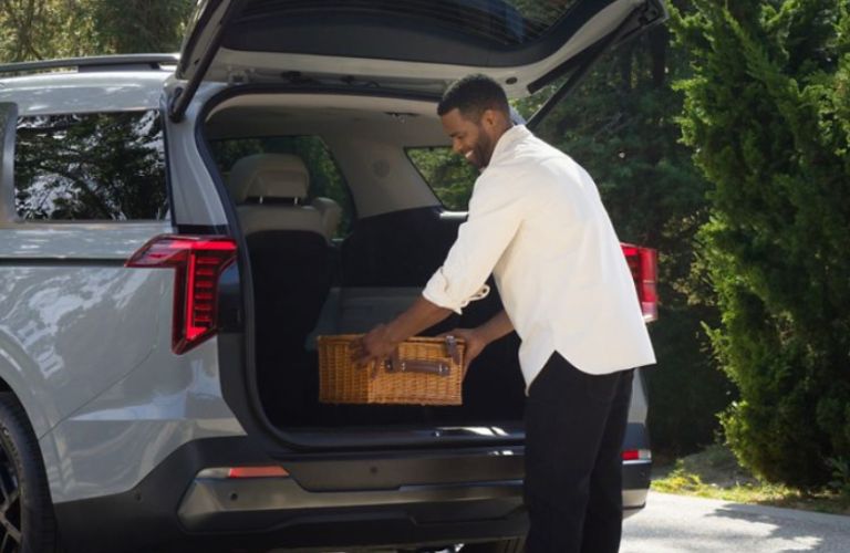 a man loading a box in the 2026 Kia Carnival MPV
