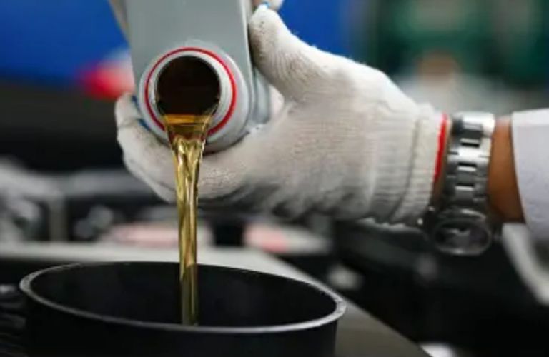 Hands of a mechanic pouring engine oil