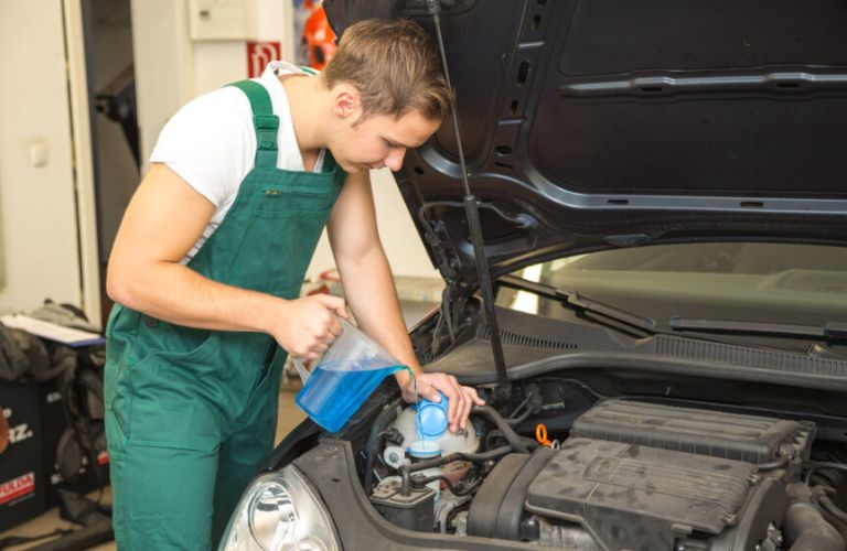 A technician measuring the coolant before refilling the radiator