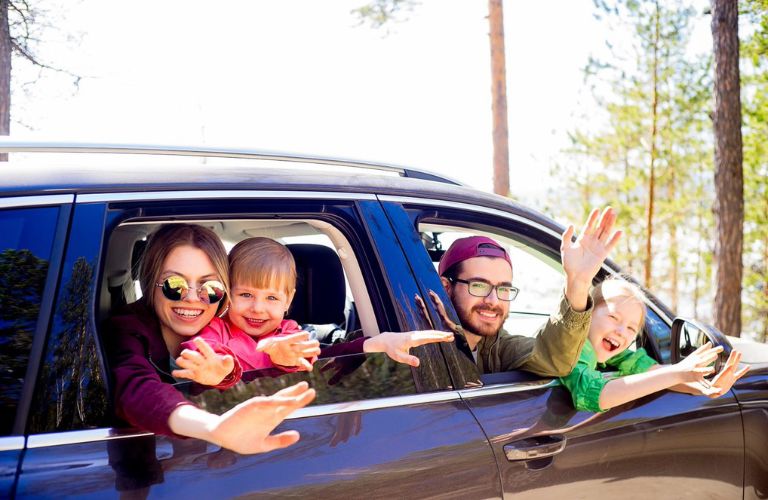 One happy couple with kids is travelling in a car.