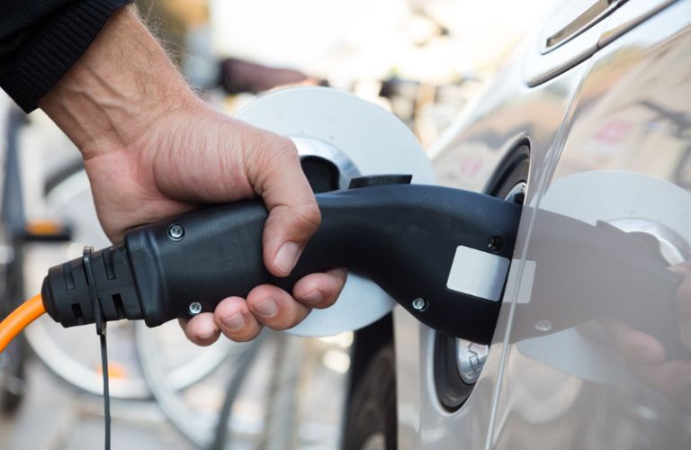 a hand charging an EV