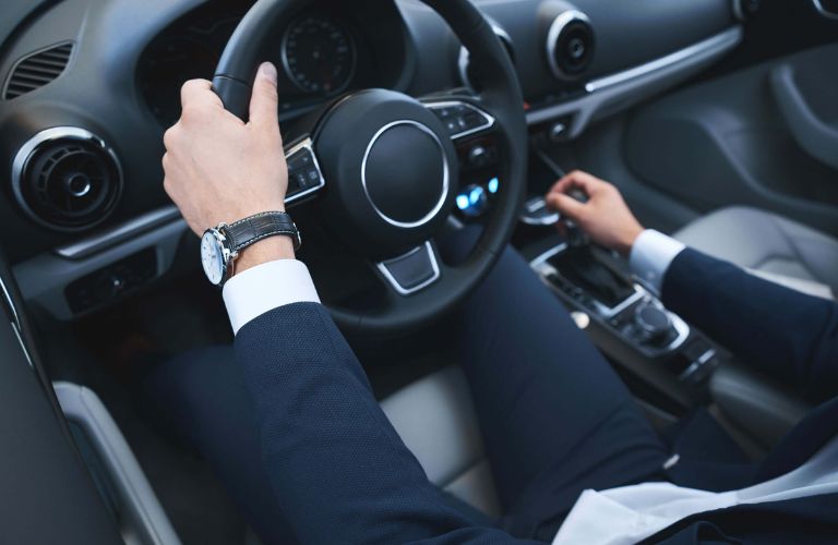 close up of a man's hands on the steering wheel of a car
