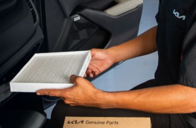a Kia technician holding a cabin filter