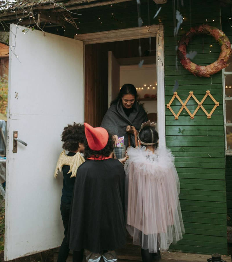 Three kids trick or treating at a home.