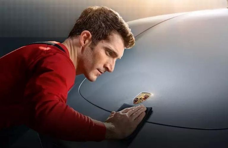 Person cleaning the hood of a Porsche