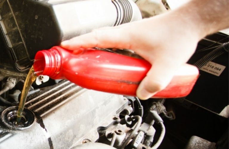 Mechanic pouring oil in a car engine