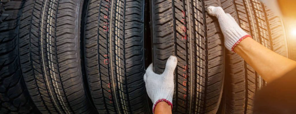 Asian male tire changer In the process of checking the condition of new tires in stock so that they can be replaced at a service center or auto repair shop. Tire warehouse for the car industry