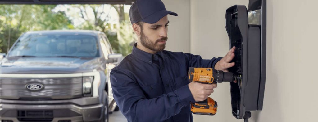 A man installing a Ford Power Promise home charging station