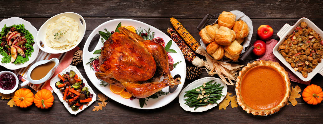 Traditional Thanksgiving turkey dinner. Top view table scene on a dark wood banner background. Turkey, mashed potatoes, dressing, pumpkin pie and sides.