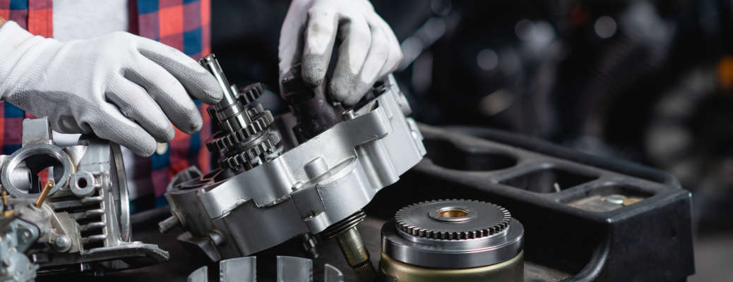 cropped view of mechanic in gloves checking disassembled transmission