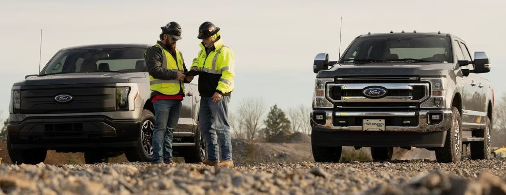 Two Ford trucks with people at a work site