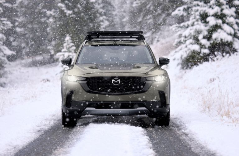 front view of the 2025 Mazda CX-50 in the snow with bright headlights