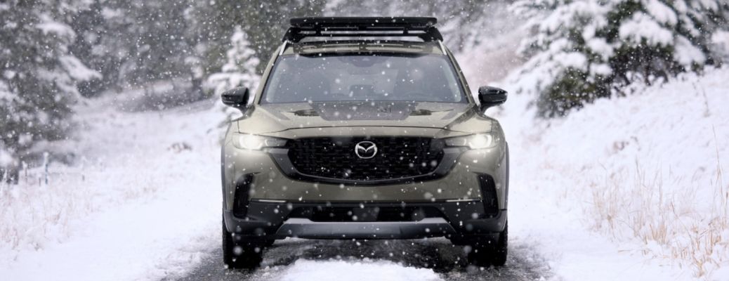 front view of the 2025 Mazda CX-50 in the snow with bright headlights