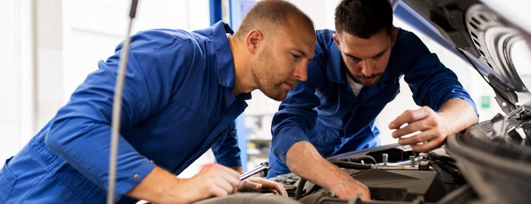 technicians checking under the hood of the car during a routine maintenance service