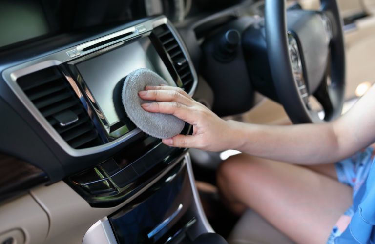 lady cleaning a car's dashboard ensuring cleanliness in the car