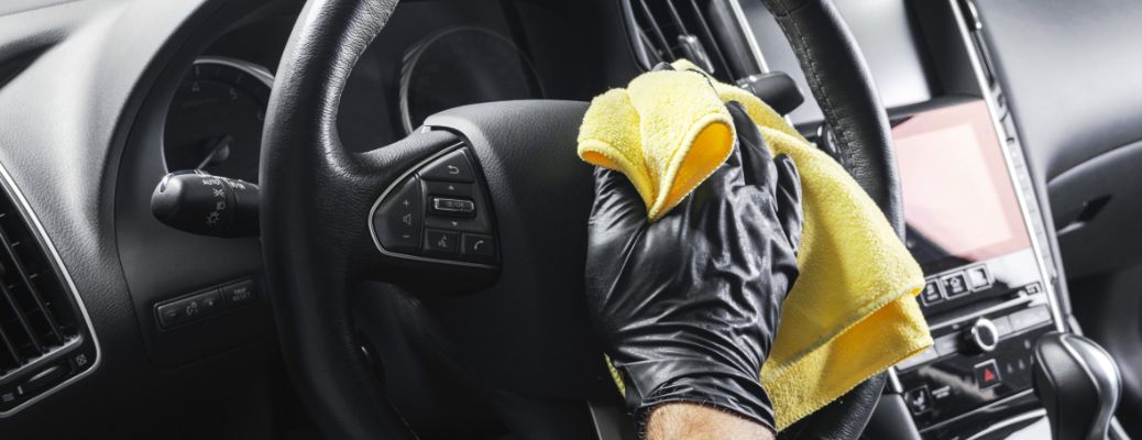 technician cleaning a steering wheel during a detailing service
