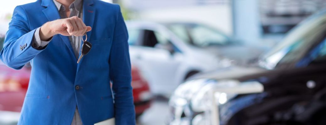 Salesperson showing a key to the camera at a dealership