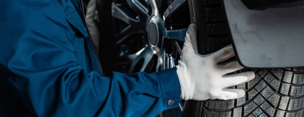 cropped view of mechanic installing wheel on car in workshop, panoramic shot - one of the top 10 ways to prep your car for winter