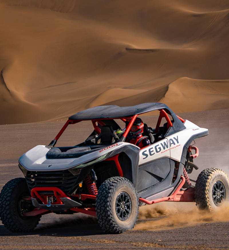 A Segway Super Villain EV ATV tearing through sand dunes