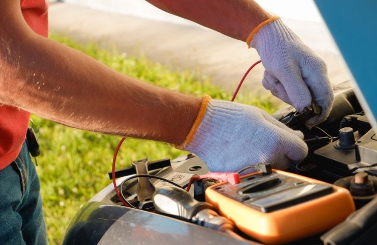 a technician's hand jump starting a battery