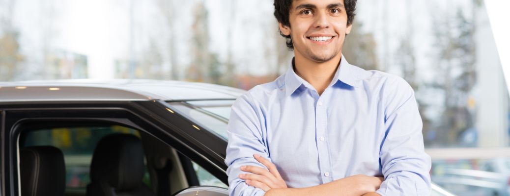 a man posing in front of a car