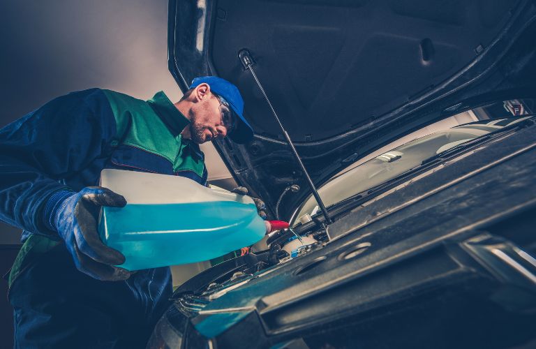 A mechanic pouring coolant in a vehicle
