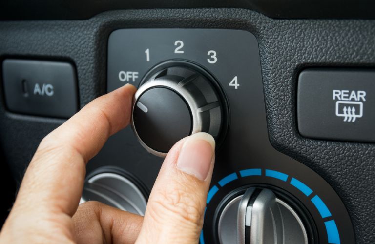 a hand accessing the A/C in a car